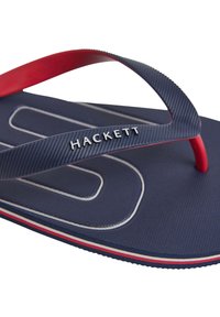 Infradito blu navy con cinturini rossi, caratterizzati da una soletta testurizzata e il logo "HACKETT" in rilievo. Accentuati da strisce bianche e rosse sulla suola.