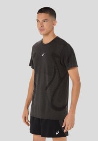 Dark gray athletic t-shirt with short sleeves, featuring textured fabric and a subtle abstract pattern. Includes a small logo on the chest.