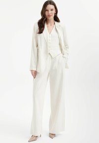 Wit gestreepte broekpak met een op maat gemaakte blazer en wijde broekspijpen. De stof heeft een gladde textuur, aangevuld met knopenaccenten.