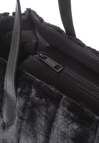 Borsa tote nera in materiale pluche con dettagli in pelle. Dotata di tasca interna con cerniera e manici robusti e piatti.