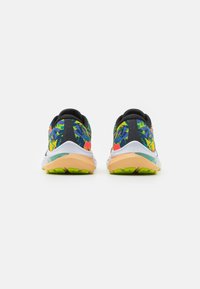 Scarpe da corsa multicolore con una tomaia a fantasia, controfondale nero, suola intermedia bianca e suola esterna verde vivace. Presentano accenti di design unici.