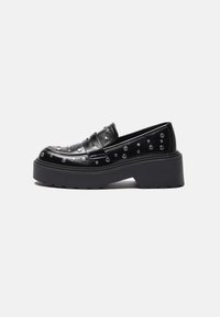 Mocassins en cuir noir avec des clous en argent, dotés d'une semelle épaisse et d'une large sangle sur le devant. Texture lisse, forme arrondie.