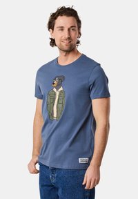 Blue cotton t-shirt featuring an illustrated dog wearing sunglasses and a green jacket. Soft texture, round neckline, and short sleeves.