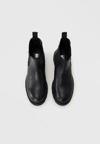 Bottines en cuir noir avec panneaux latéraux élastiques, semelles en caoutchouc texturé et languettes de traction pour un enfilage facile. Fini lisse et design à bout rond.
