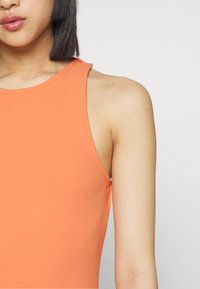 Top laranja sem mangas feito de tecido elástico, com um decote arredondado e ombros sem costuras, destacando uma textura suave.