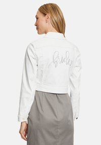 Witte cropped denimjacket met "Bride" in rhinestone op de rug. Lange mouwen met knoopmanchetten, klassiek kraagontwerp.