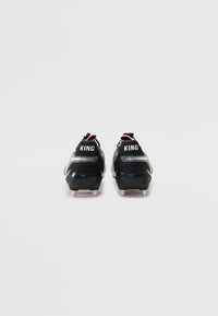 Black sports cleats with silver accents, textured surface, and red details. "KING" printed on the back, featuring multiple studs for traction.