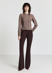 Brauner Strickpullover mit Peplum-Saum und strukturiertem Muster. Getragen mit dunkelburgunderfarbener, ausgestellter Hose und bordeauxfarbenen High Heels.