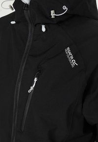 Veste imperméable noire Regatta avec poche zippée verticale, cordons de capuche réglables et logo blanc sur la poitrine.
