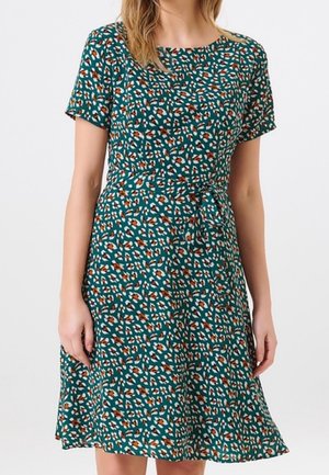 Robe verte à manches courtes avec une taille cintrée, ornée d'un motif abstrait orange et blanc dispersé, et d'une jupe évasée fluide.