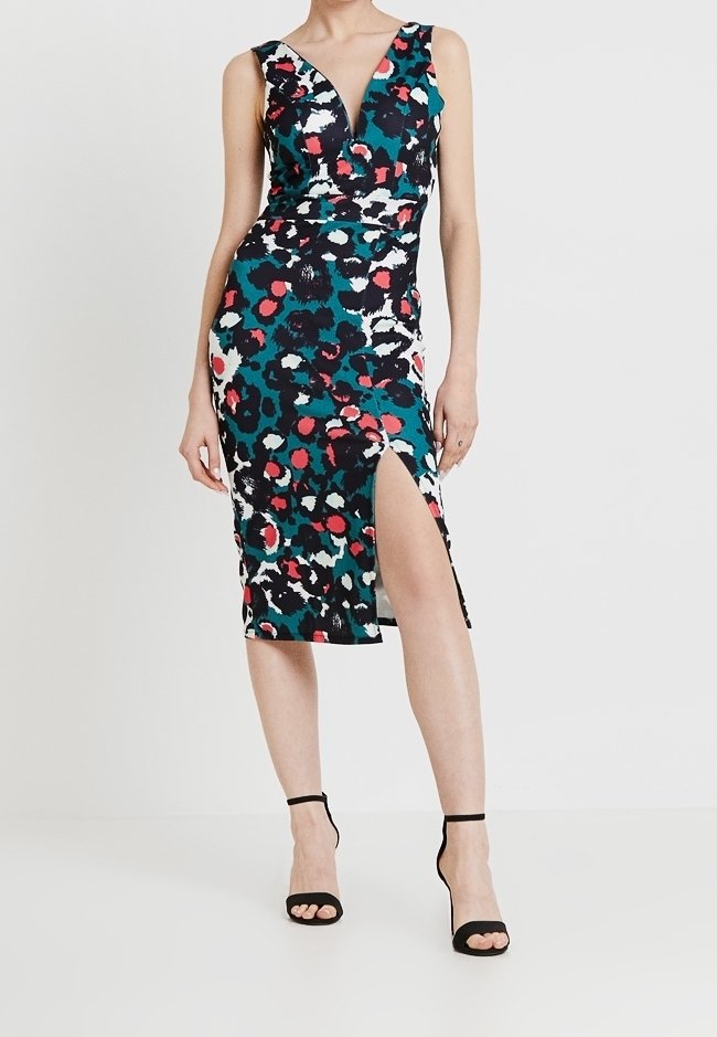 Robe sans manches, longueur genou, avec un décolleté en V profond, présentant un imprimé animal multicolore en vert, noir, rouge et blanc, avec une fente latérale.
