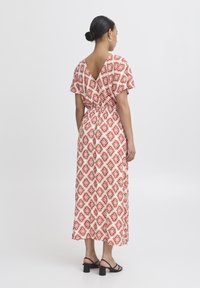 Abito lungo con un motivo geometrico rosso e bianco, design con scollatura a V sul retro, maniche corte a volant e vita elastica per una silhoutte aderente.