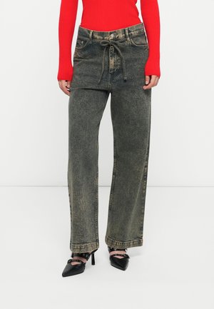 Wide-leg, acid-wash jeans in dark grey denim, featuring a drawstring waistband and front pockets, paired with pointed black heels.
