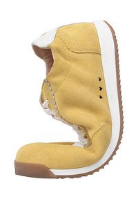 Żółty zamszowy but sportowy zgięty na pół, pokazujący białą gumową podeszwę z brązowym bieżnikiem oraz wewnętrzne białe futerko.