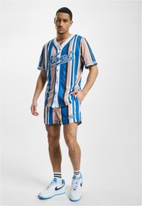 Košile s krátkým rukávem a kraťasy v modro-bežných pruzích. Obsahuje logo na prsou a ladící kraťasy, vyrobené z hladké tkaniny.