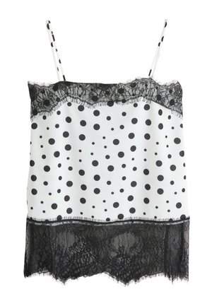 Camisole blanche avec des pois noirs, bordure en dentelle noire sur les bords supérieur et inférieur, et fines bretelles avec motif à pois.