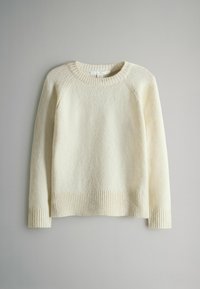 Kremowy sweter o teksturowanym splotach, z prążkowanym okrągłym dekoltem i mankietami. Długie rękawy o luźnym kroju, w jednolitym kolorze z minimalnymi detalami.