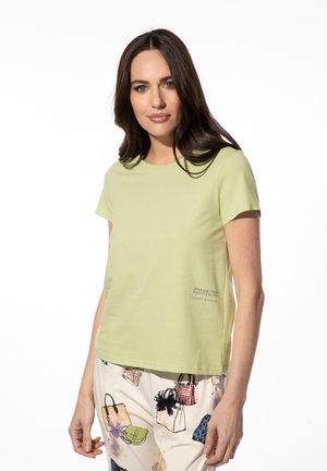 Helles grünes T-Shirt mit kurzen Ärmeln aus weicher Baumwolle und Rundhalsausschnitt; auf der Vorderseite mit dem aufgedruckten Text "UPGRADE YOUR BODYFEELING SHORT STORIES".