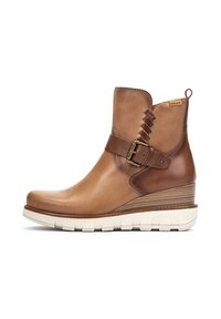 Bottine en cuir marron avec un talon compensé, présentant une sangle latérale avec détail de boucle, des accents texturés et une semelle en caoutchouc blanche.