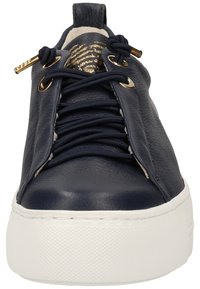 Sneakers en cuir marine avec une semelle en caoutchouc blanc, dotées de quincaillerie dorée, de lacets élastiques et d'une finition texturée sur le dessus.
