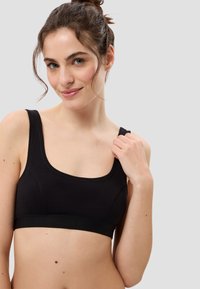 Schwarzer Sport-BH mit breiten Trägern, Rundhalsausschnitt und figurbetonter Passform. Glattes Material mit einem umsäumten unteren Saum und minimalen Nahtdetails.