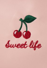 Il tessuto rosa presenta un testo ricamato in rosso che legge "Sweet-life" con due ciliegie e foglie verdi sopra, evidenziando un design giocoso.