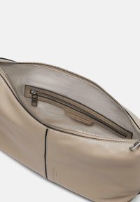 Beige Lederhandtasche innen, mit glatter Textur, Reißverschlusstasche und Markenetikett. Schlichtes, minimalistisches Design mit einem geräumigen Fach.