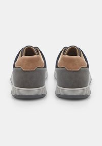 Navy and tan sneaker with a smooth gray base, round toe, cushioned heel, and a textured upper, featuring subtle stitching details.