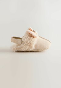 Pantoufle beige en fourrure avec un dessus texturé doux, ornée d'un nœud en tissu rose et d'un design à l'arrière fermé pour un meilleur maintien.