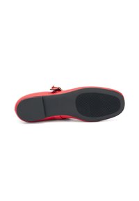Zapato de cuero rojo con textura suave, que presenta una puntera redonda y una suela de goma negra. Un hebilla dorada adorna el costado.