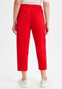 Red cropped pants made of lightweight fabric, featuring an elastic waistband, two back pockets, and a straight-leg design.