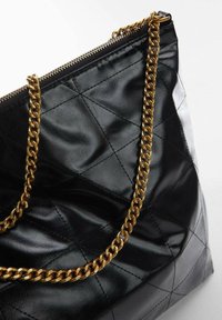 Sac à main en cuir matelassé noir avec une bandoulière en chaîne dorée, doté d'une fermeture éclair et d'une texture lisse et brillante.