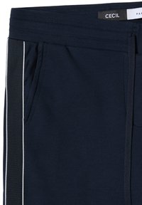 Granatowe spodnie dresowe z teksturowanego materiału, z bocznymi kieszeniami, białymi bocznymi paskami oraz ściągaczem w pasie na troczki. Widoczna metka marki.