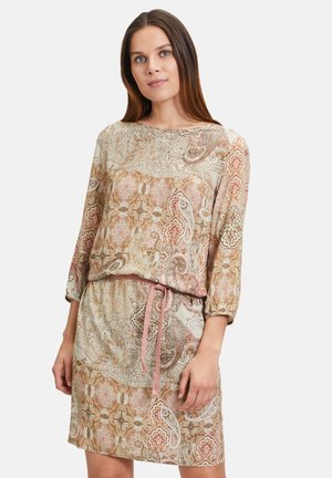 Ein Kleid mit Paisleymuster und langen Ärmeln, tailliert mit einem pinkfarbenen Band, in erdigen Tönen von Beige, Rost und Creme. Leichter, strukturiert Stoff.