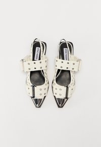 White slingback heels featuring a pointed toe, studded accents, wide buckle straps, and a glossy metallic heel.