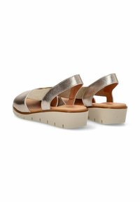 Sandalias metálicas doradas con punta redonda y banda elástica. Presentan una plantilla beige y una suela gruesa de color crema con relieves.