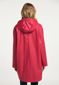 Cappotto impermeabile rosso con un ampio cappuccio, maniche lunghe e linea dritta. Presenta chiusure a pressione sui polsini, realizzato in materiale liscio.