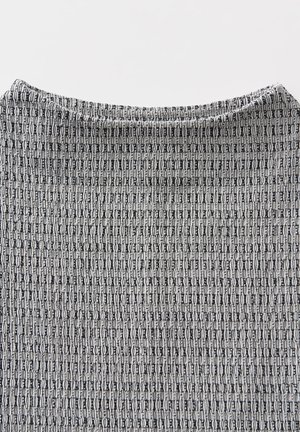 Haut tricoté présentant un motif gris et noir avec des formes allongées. Texture lisse et encolure large avec un léger détail de côtes.