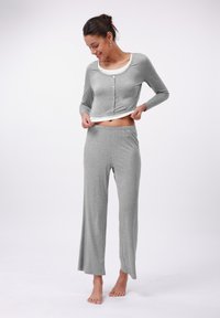 Haut de pyjama gris à manches longues avec des boutons et un col arrondi, associé à un pantalon large gris assorti. Tissu doux et léger.