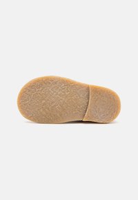 Semelle de chaussure en caoutchouc marron avec une surface texturée et un talon arrondi, présentant un motif de semelle prononcé pour l'adhérence et la durabilité.