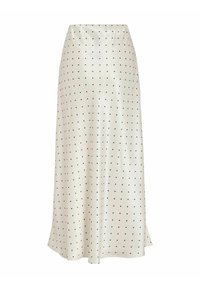Une longue jupe en satin couleur crème avec une texture lisse, présentant un motif de petits points noirs et une fente latérale pour faciliter le mouvement.
