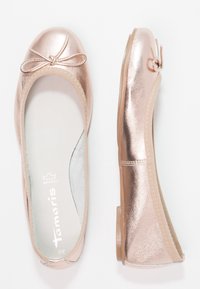 Bailarinas en oro rosa con acabado metálico, punta redondeada y un pequeño lazo decorativo. Cinta elástica alrededor de la apertura para un ajuste seguro.