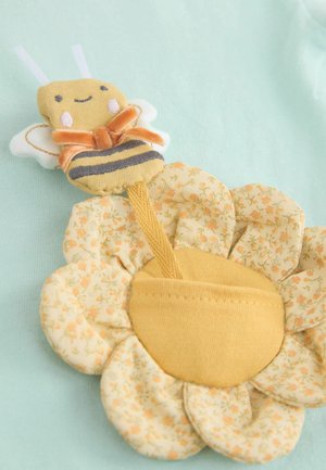 Emblema textil cu o albină zâmbitoare deasupra unei flori galbene, cu modele florale. Albina are aripi albe și un accent cu funda portocalie.