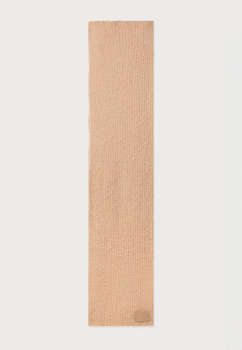 Bufanda tejida beige con un patrón texturizado. Presenta un acabado suave y una pequeña etiqueta rectangular en la esquina inferior.