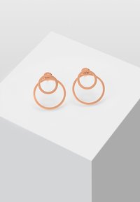 Øreringer i roségull med to sirkulære sølvringer med en polert finish. Den større ringen omgir en mindre, noe som skaper en lagdelt effekt.