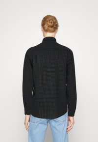 Camicia a maniche lunghe con bottoni in tartan verde scuro e blu navy. Realizzata in tessuto morbido con colletto standard e orlo curvo. Presenta polsini con bottoni.