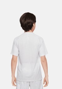 Camiseta atlética corta blanca con mangas cortas, espalda de malla texturizada, frente liso y escote acanalado. Adecuada para deportes o ropa activa.