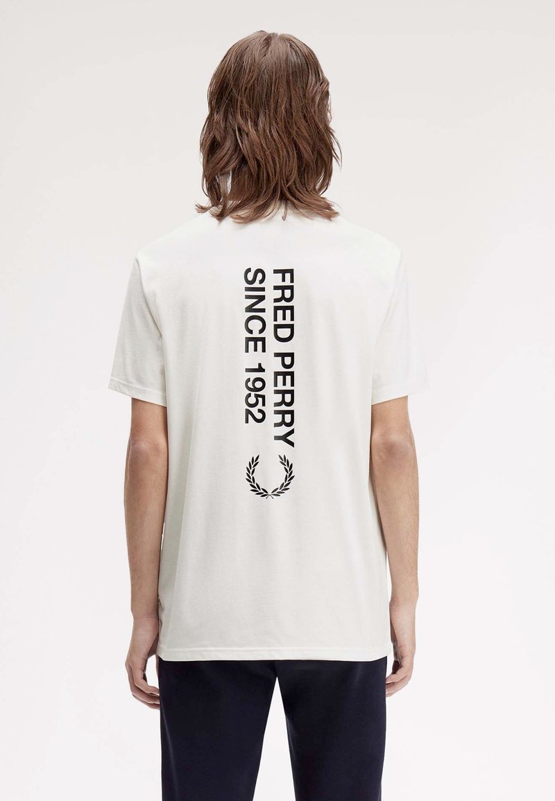 Weißes Baumwoll-T-Shirt mit schwarzem Text auf dem Rücken: "FRED PERRY SEIT 1952" und einem schwarzen Lorbeerkranz-Design. Kurze Ärmel, normale Passform.