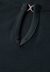 Czarny top z dekoltem w kształcie klucza i srebrnym metalowym akcentem. Materiał jest gładki, o mocno tkanym splocie i minimalnych detalach szycia.