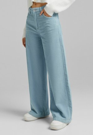 Pantalones de pana azul claro de pierna ancha con cintura alta, que cuentan con cierre frontal de botones, bolsillos laterales y textura acanalada vertical.